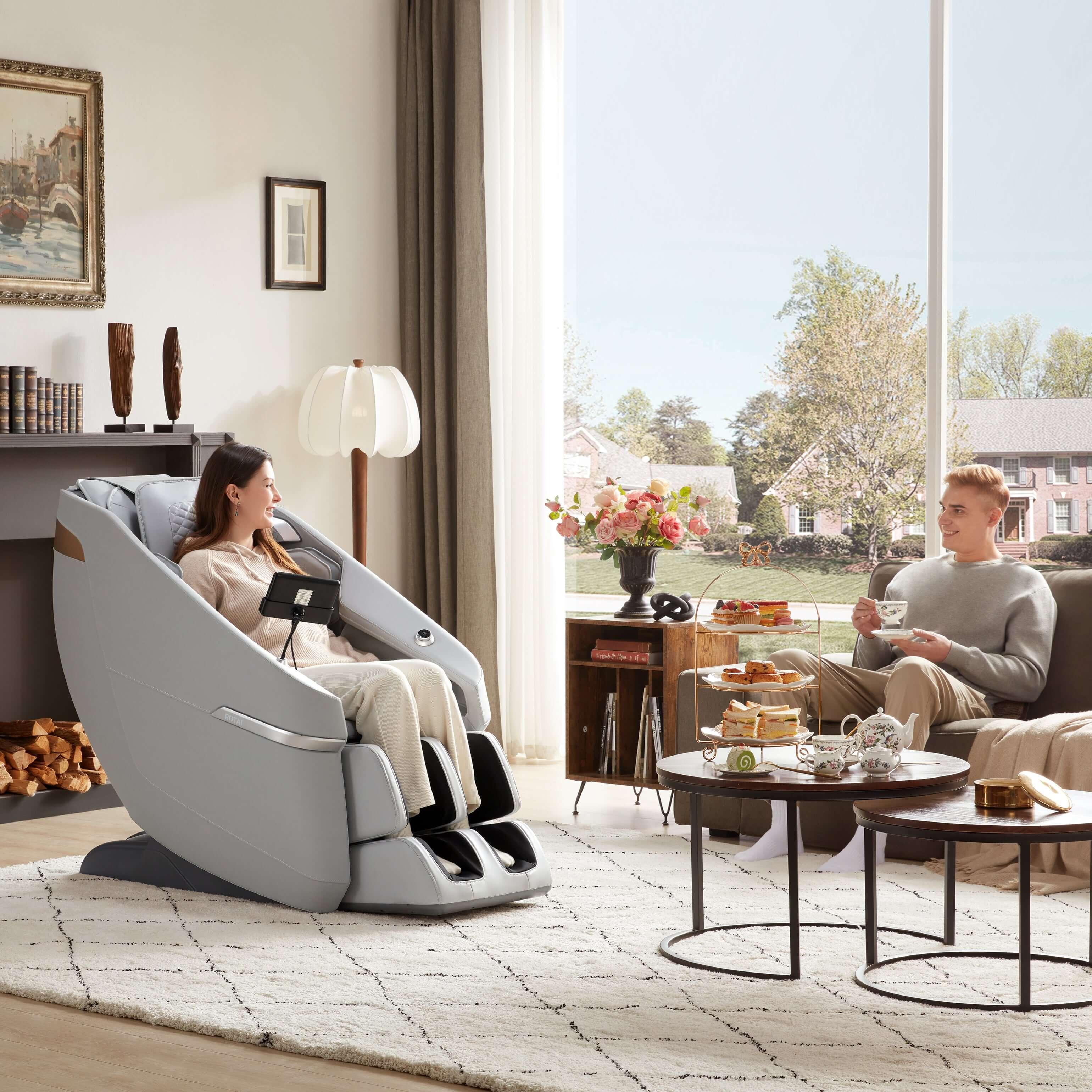 Woman using Ekanite Massage Chair and Sofa in living room with tablet control while man relaxes, showcasing best massage chair in UAE.